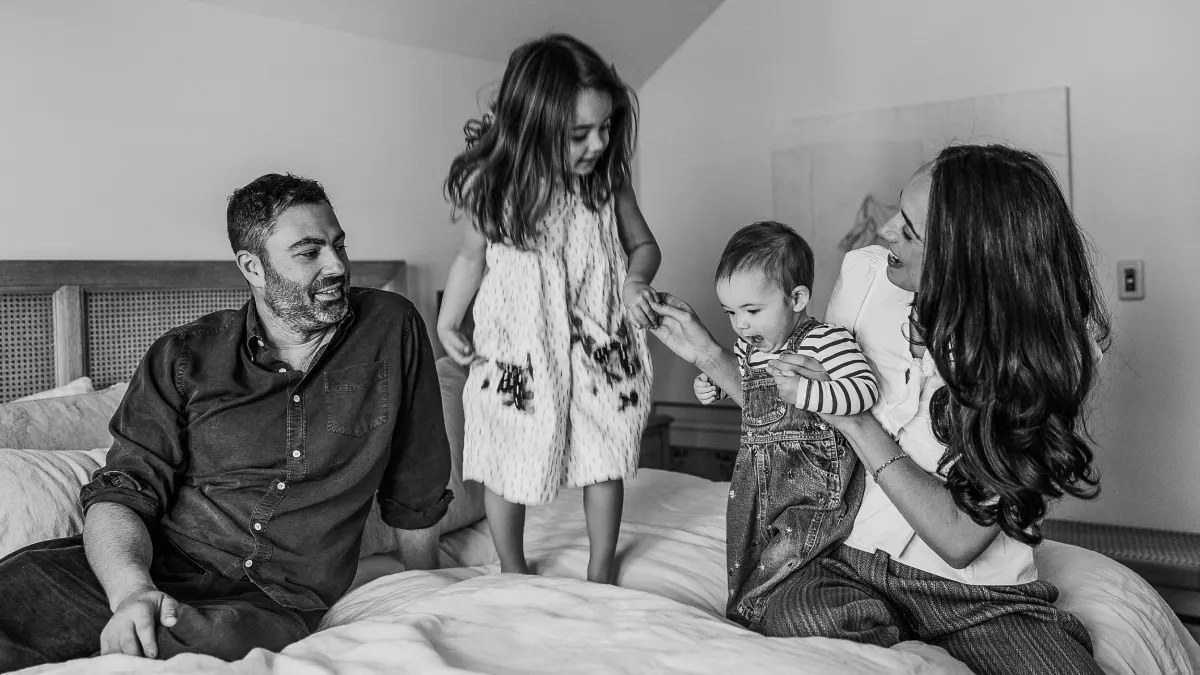 Eric Markowitz with his wife and two young daughters on a bed